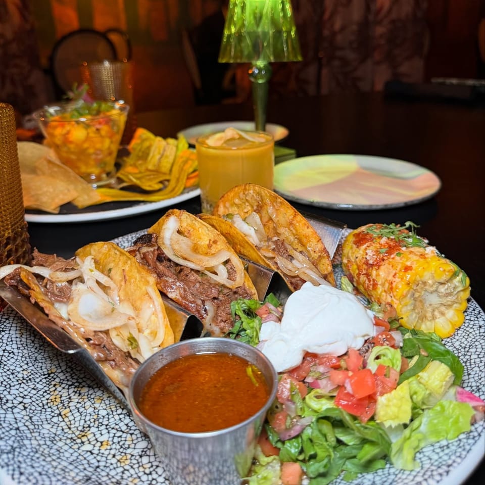 Havana 151 tacos with beef, onions, corn, salad, and sauce, on a patterned plate.