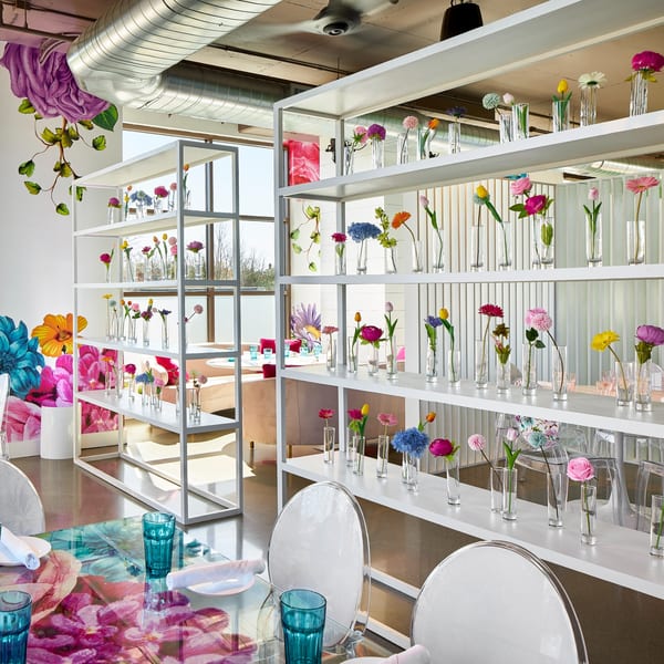 Havana 151's bright dining room with white shelves displaying colorful flowers and floral-patterned tables.