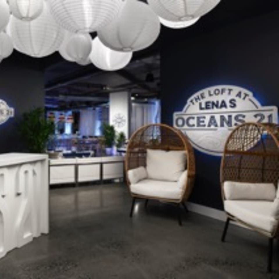 Lobby area with white paper lanterns, two wicker chairs, and a sign for "The Loft at Lena's Oceans 21".