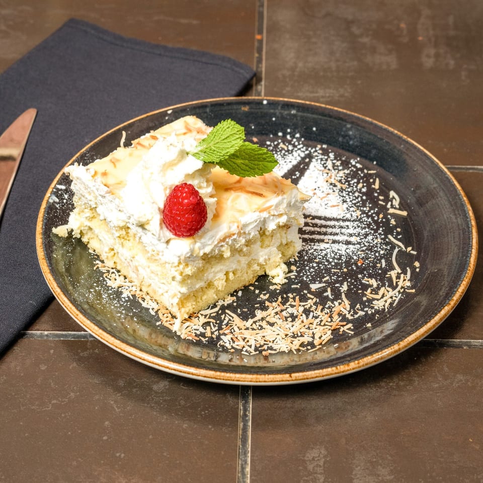 A slice of Havana 151's tres leches cake, topped with whipped cream, a raspberry, and mint.