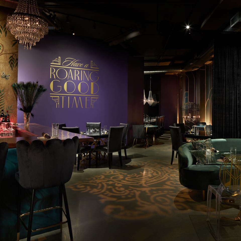 Havana 151's dimly lit dining room with purple walls, chandeliers, and elegant seating.