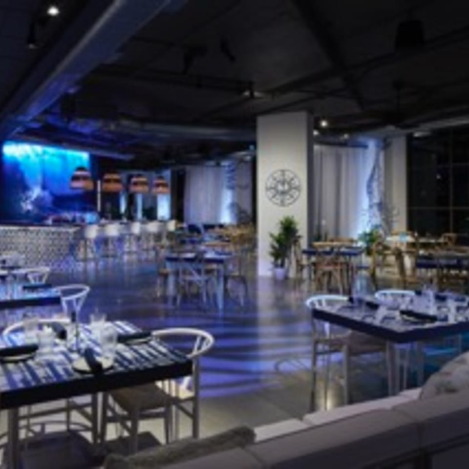 The Loft at Lena's, a dimly lit Cuban restaurant with blue lighting, tables, and a bar area.