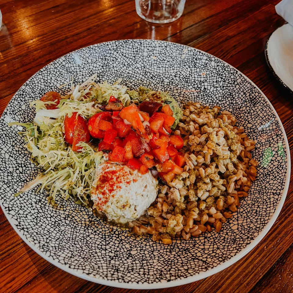 A Cuban bowl with rice, shredded lettuce, diced tomatoes, guacamole, and a dollop of white sauce.