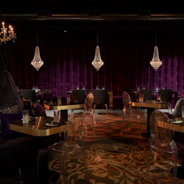 Elegant dining room at Havana 151 with purple velvet curtains, crystal chandeliers, and gold tables.