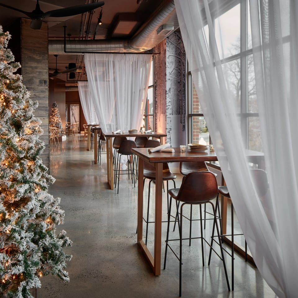 A festive Havana 151 dining room with tall tables, bar stools, and frosted Christmas trees.