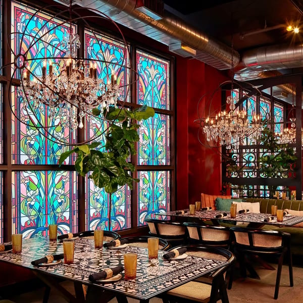 Havana 151's dining room features ornate chandeliers, stained glass windows, and patterned tables with wicker chairs.